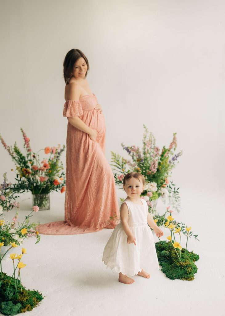maternity photos with toddler playing with flowers