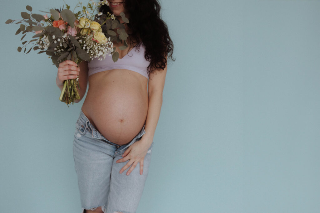 flower bouquet in maternity photo showing belly with blue background